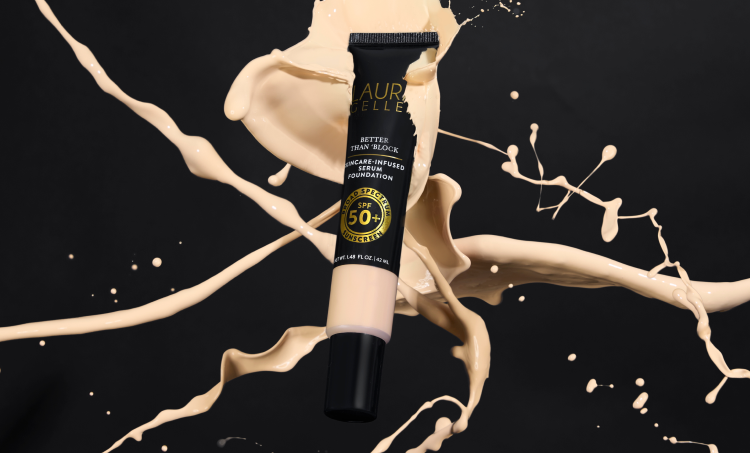 Cosmetic tube with Laura Geller logo on a black background with product splashes