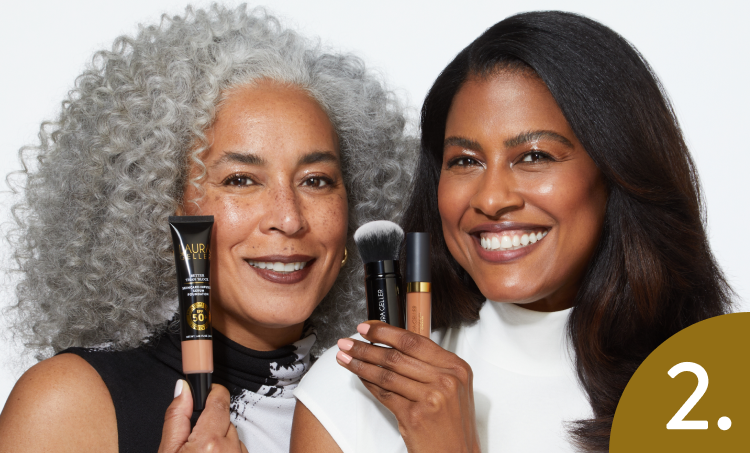 Two women hold Laura Geller face makeup products