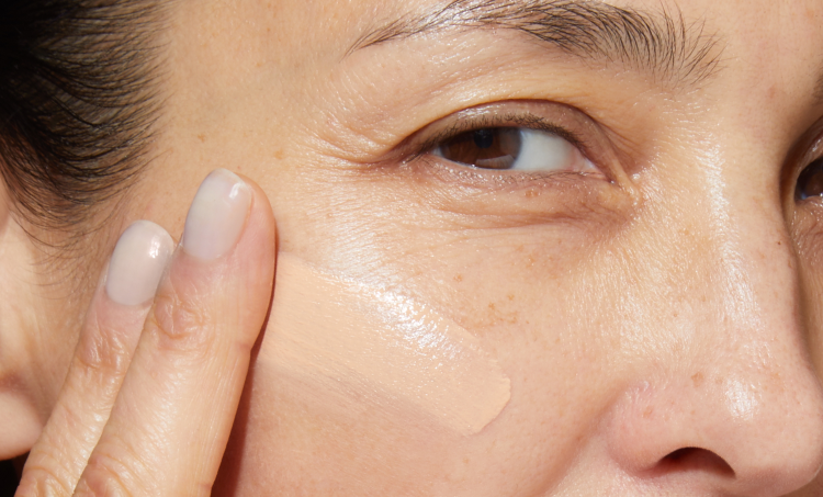 Close-up of a person applying Laura Geller foundation to their face