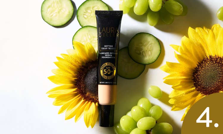 Laura Geller foundation tube with sunflowers, cucumbers, and grapes on a white background