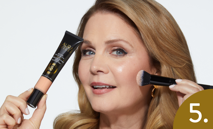 Woman applying Laura Geller Better Than Block with a brush and a tube of cream, against a white background.