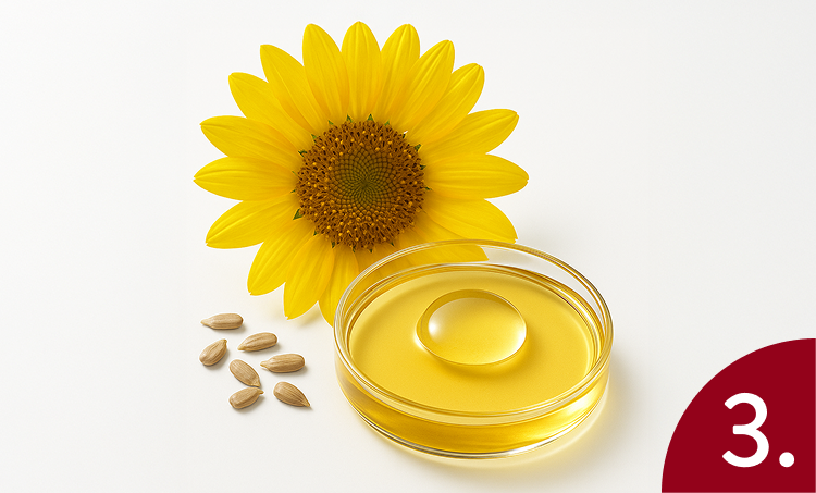 Sunflower oil in a glass container with sunflower seeds and a sunflower on a white background