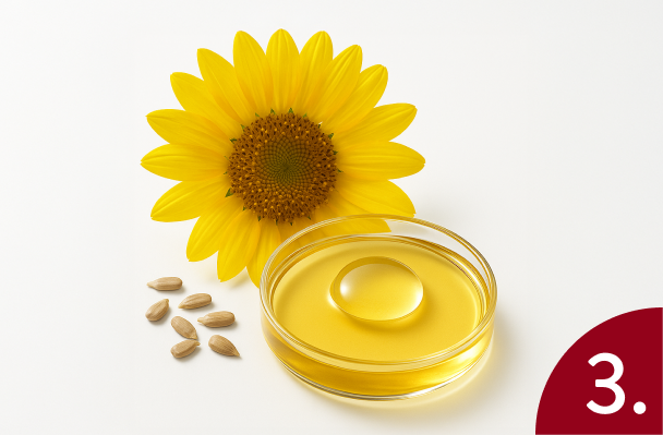 Sunflower oil in a glass container with sunflower seeds and a sunflower on a white background