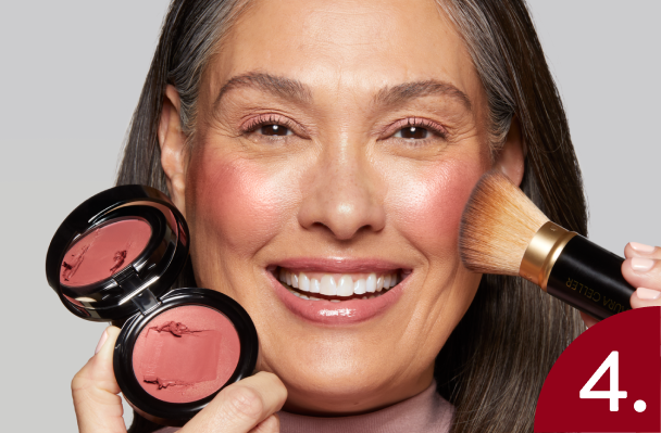 Woman applying Laura Geller Wonder Balm with a brush on a gray background