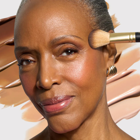 Model applying makeup with liquid foundation swatches behind her