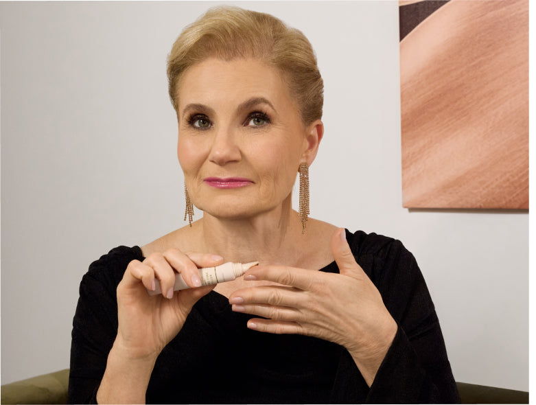Woman applies Laura Geller Line Smoother on her finger.