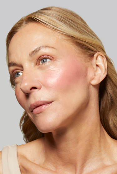 Close-up of a woman's face wearing Laura Geller's wonder Balm with a neutral background